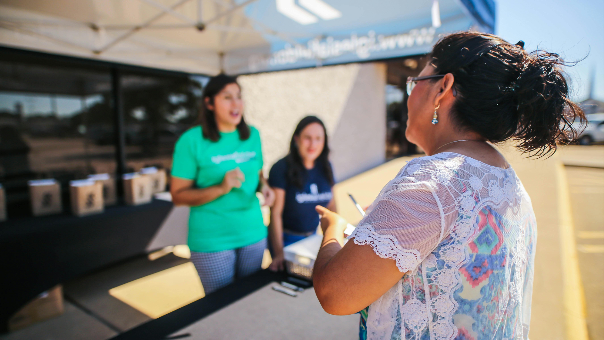 Woman talking with vendors at a table during community event