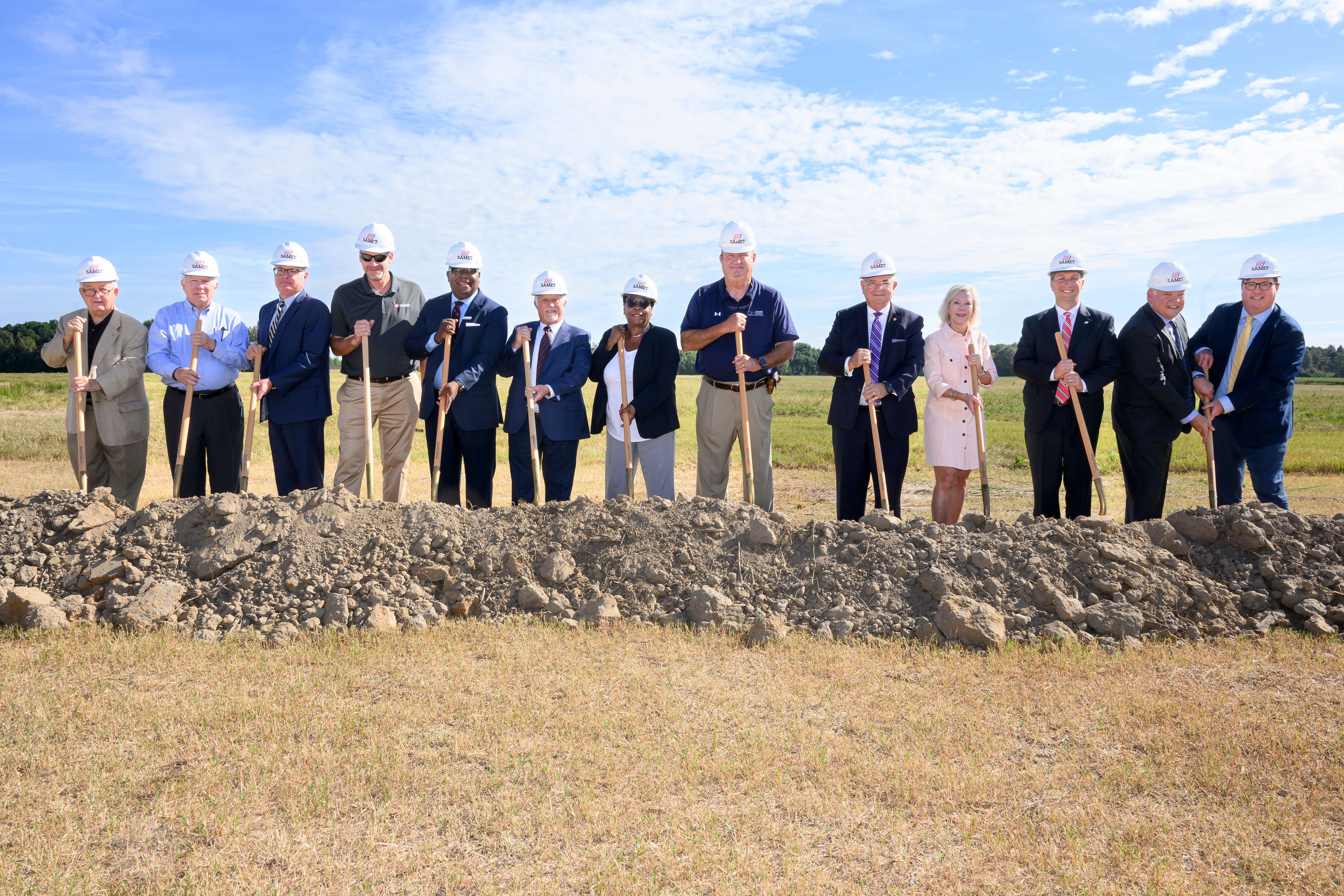 13 individuals at the groundbreaking holding shovels 