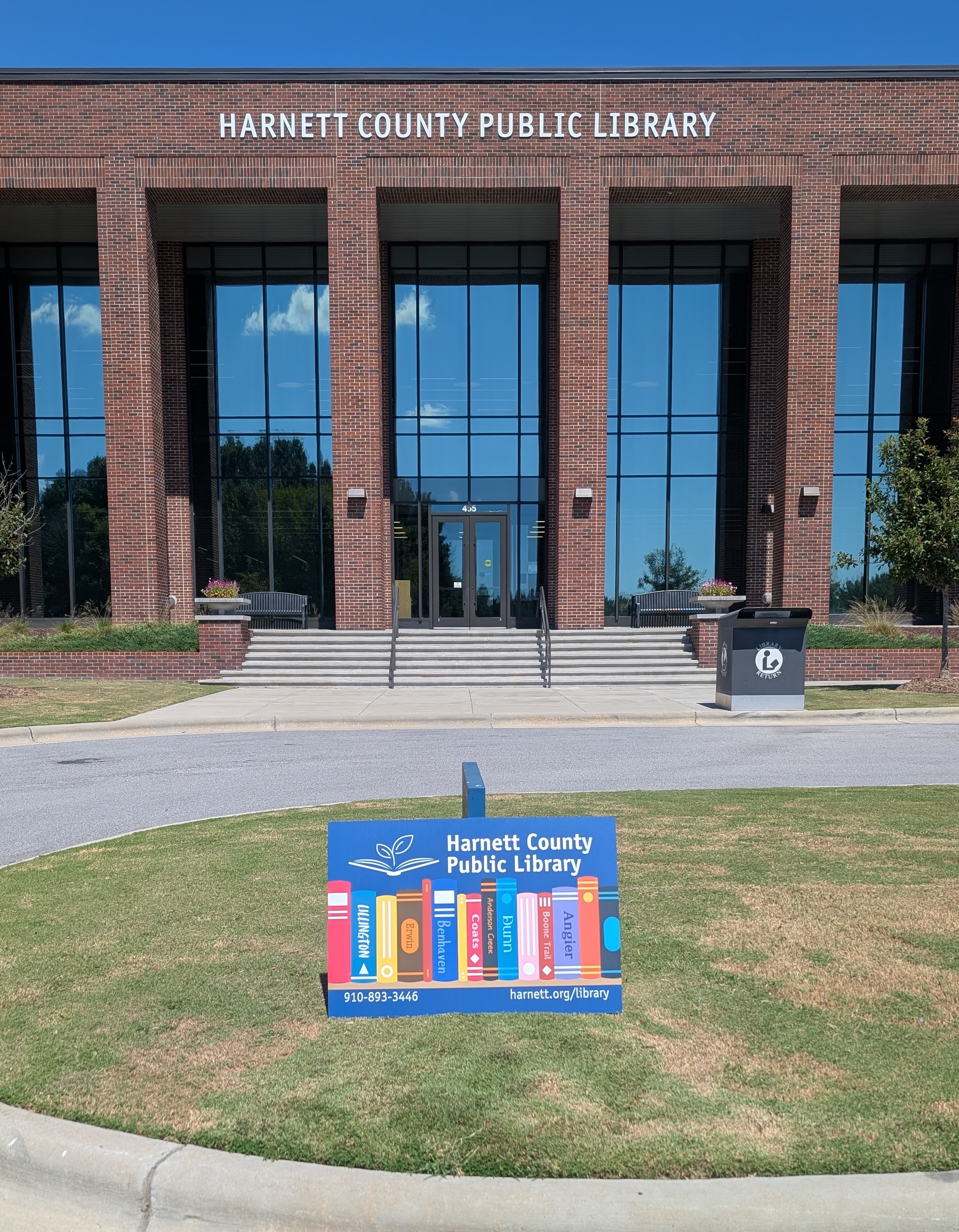 Picture of the Main Library branch and the Library Card sitting in the grass